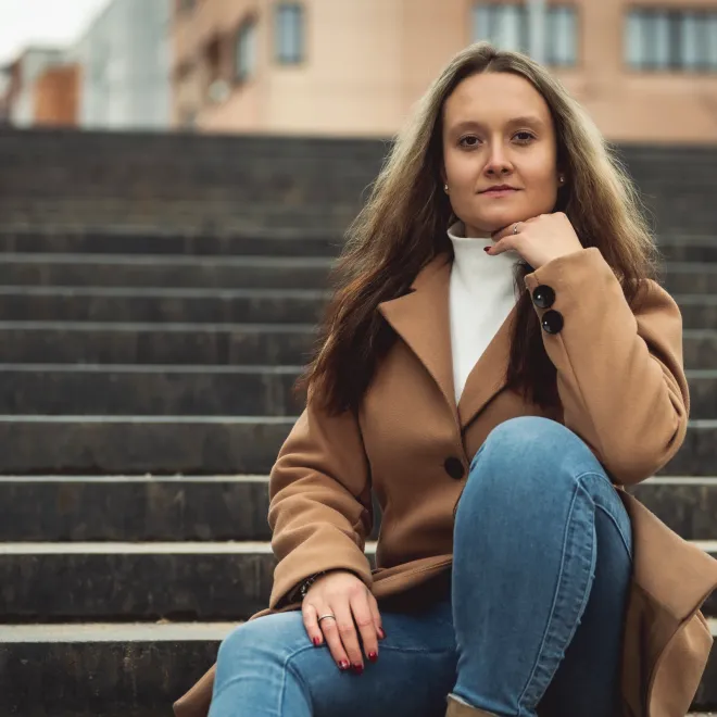 Žena v kabátu na kamenných schodech v centru města